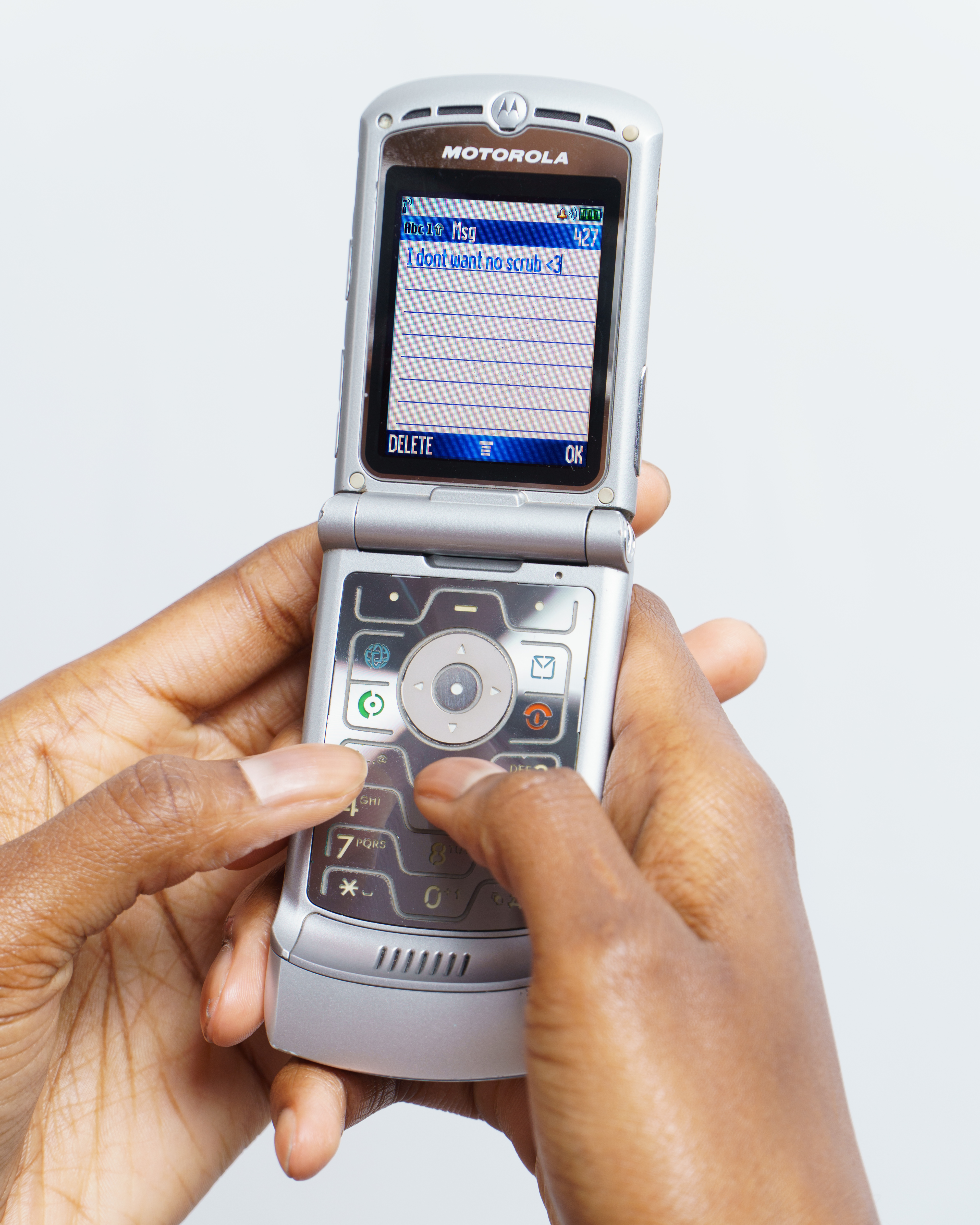 black woman's hands holding motorolla razr v3 cell phone